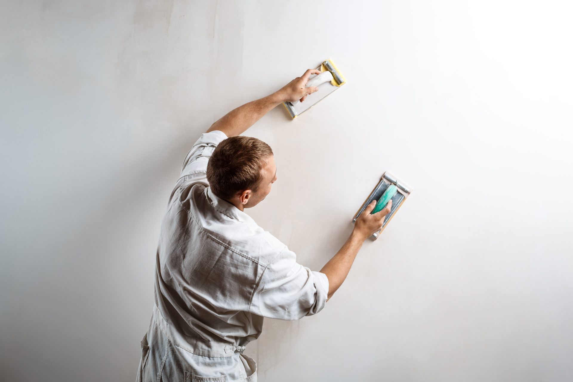 worker grinding white wall with sandpaper. copy space.
